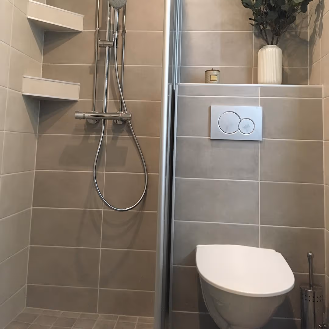 Modernissa kylpyhuoneessa on laatoitetut seinät, suihku hanoineen ja seinä-WC.
