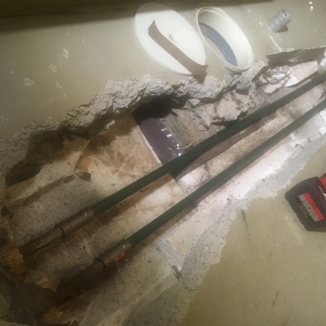 Avatussa betonilattiassa näkyy kaksi vihreää putkea, jotka ovat osa putkistoa.